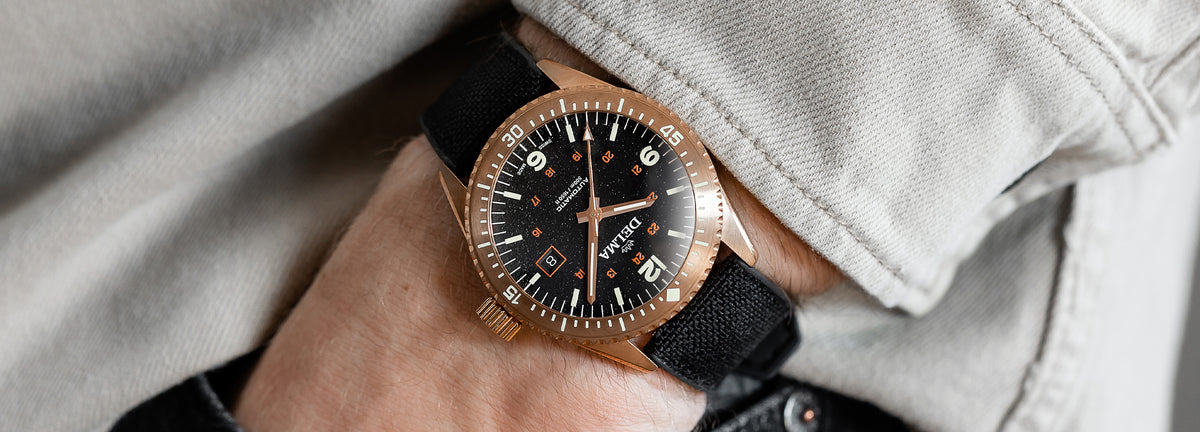 DELMA Cayman Bronze watch with black dial and black Cordura strap on wrist