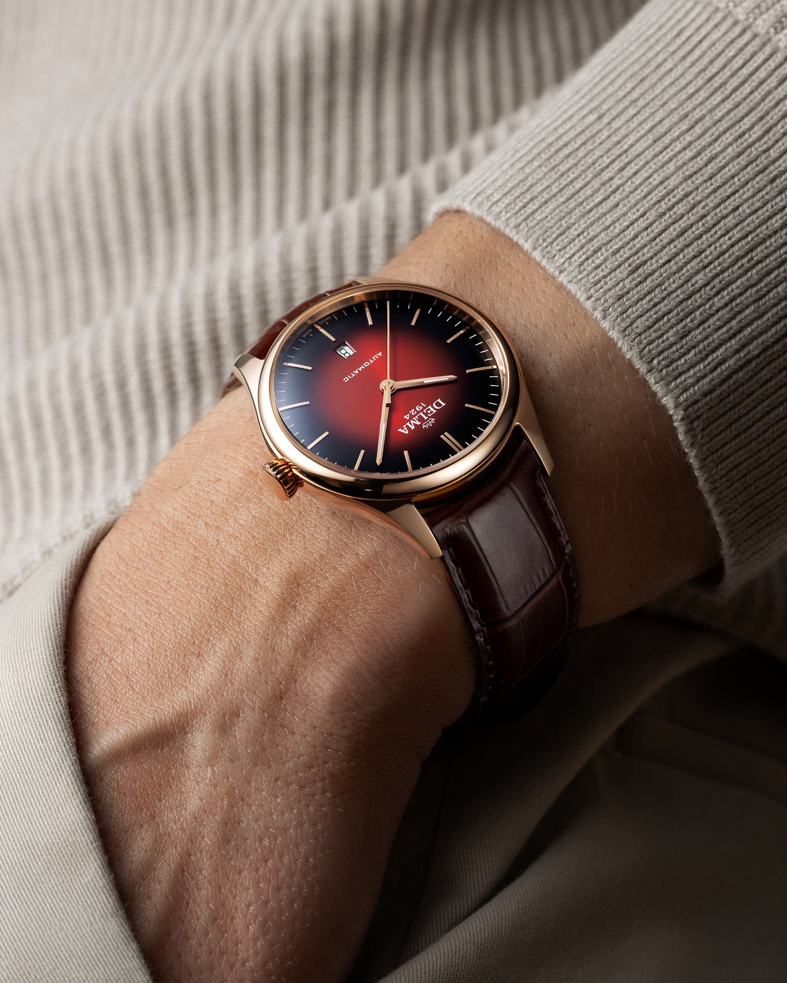 DELMA Heritage Automatic stainless steel and rose gold PVD watch with red fumé dial and brown leather strap on wrist