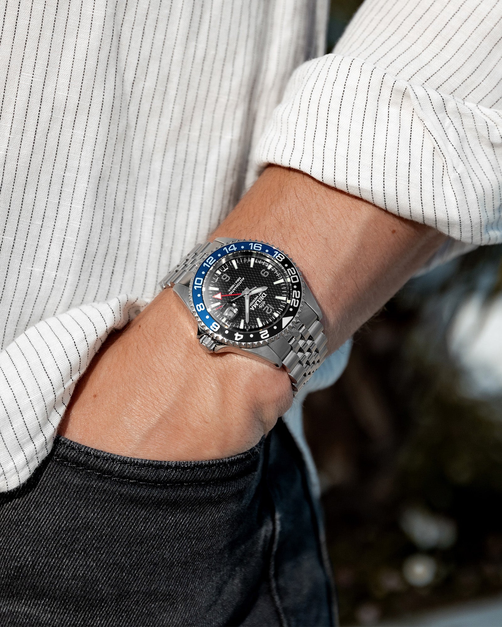 DELMA Santiago GMT Meridian Automatic stainless steel watch with black dial and black and blue bezel on wrist