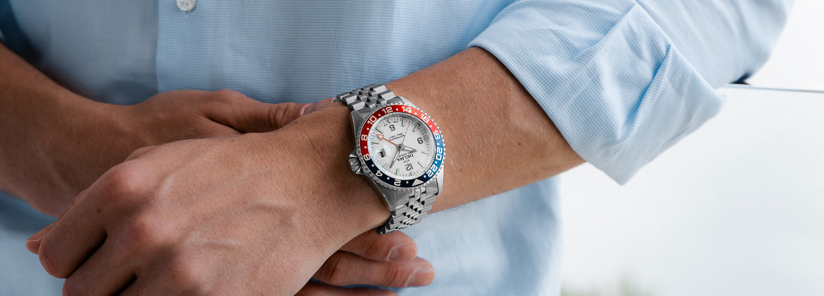 DELMA Santiago GMT Meridian Automatic stainless steel watch with white dial and blue and red bezel on wrist