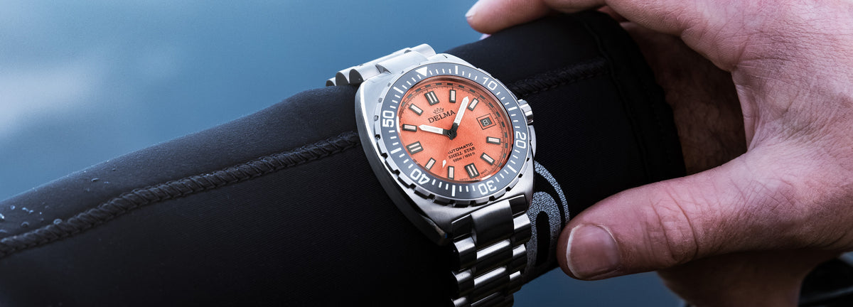 DELMA Shell Star Titanium watch with orange dial and black bezel on diver