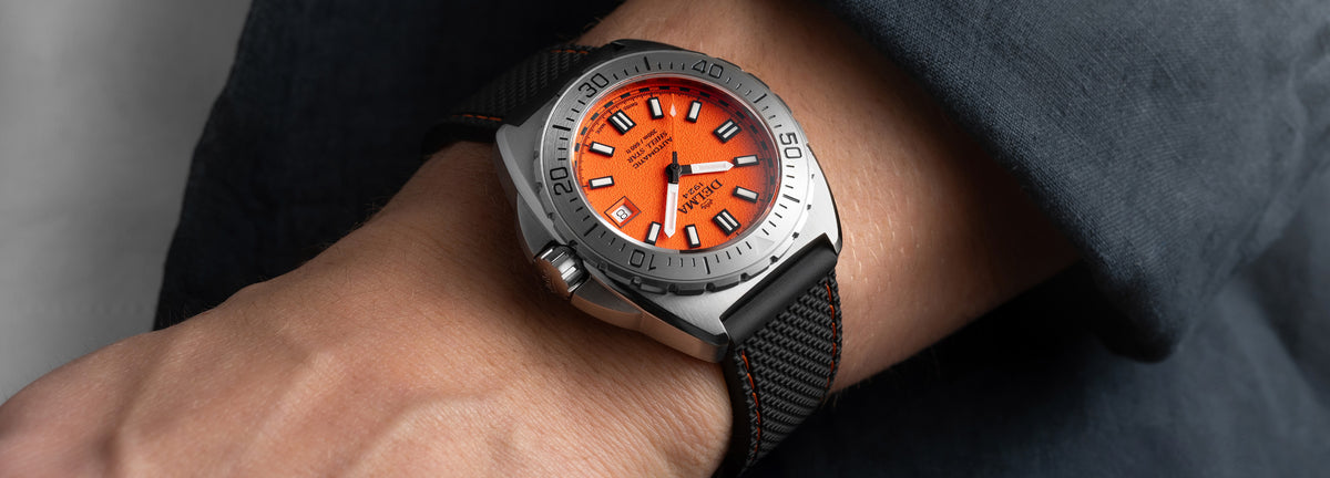DELMA Shell Star 41 mm stainless steel watch with orange dial and black rubber strap on wrist