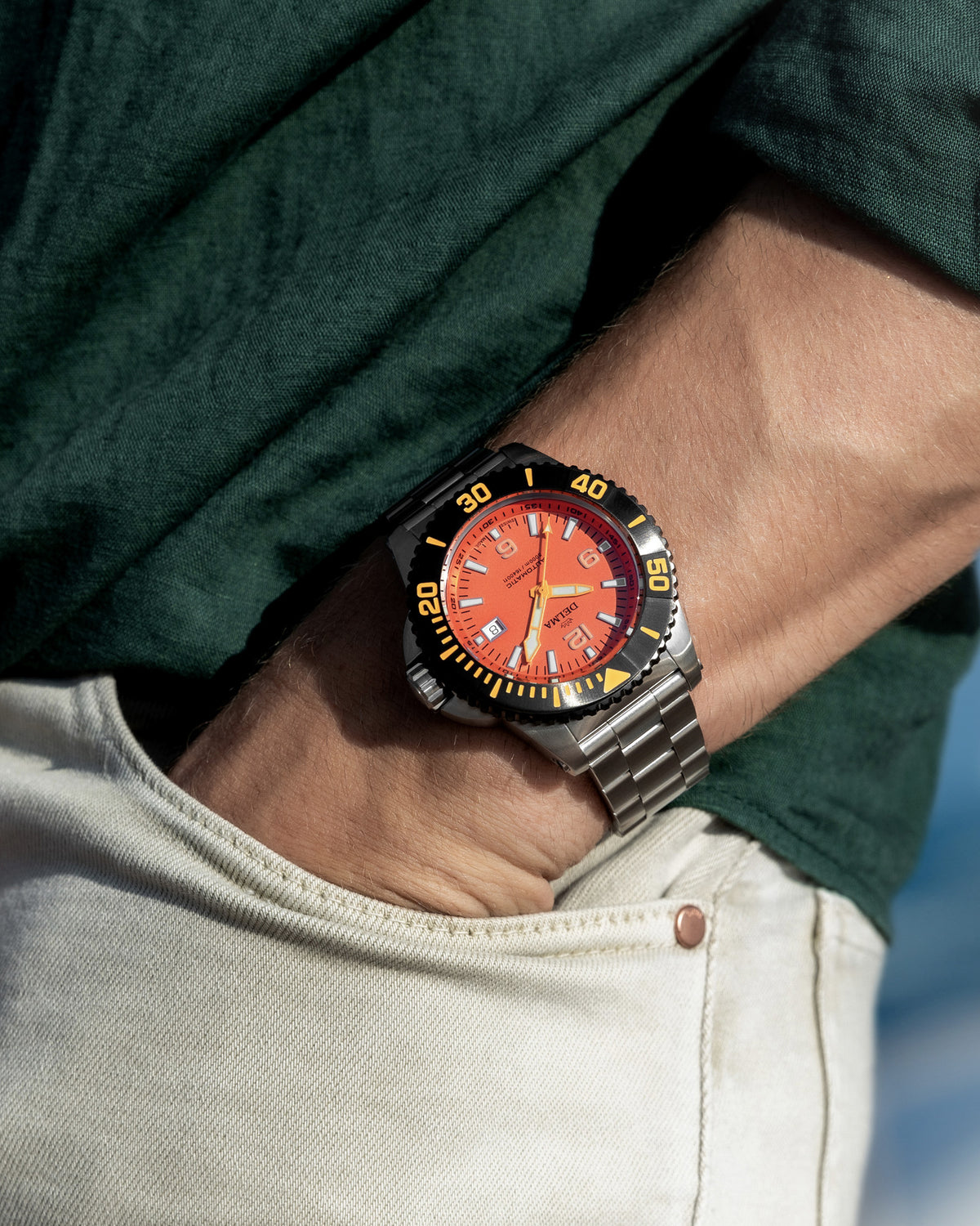 DELMA Blue Shark IV stainless steel watch with orange dial and black bezel on wrist