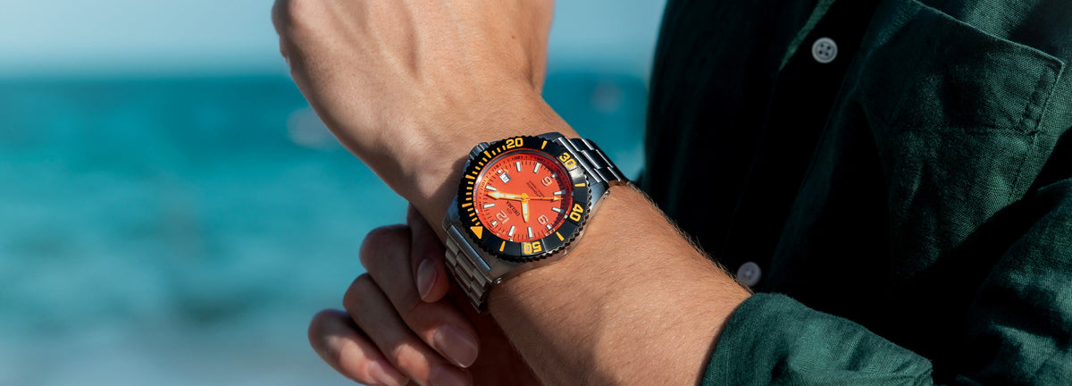 DELMA Blue Shark IV stainless steel watch with orange dial and black bezel on wrist