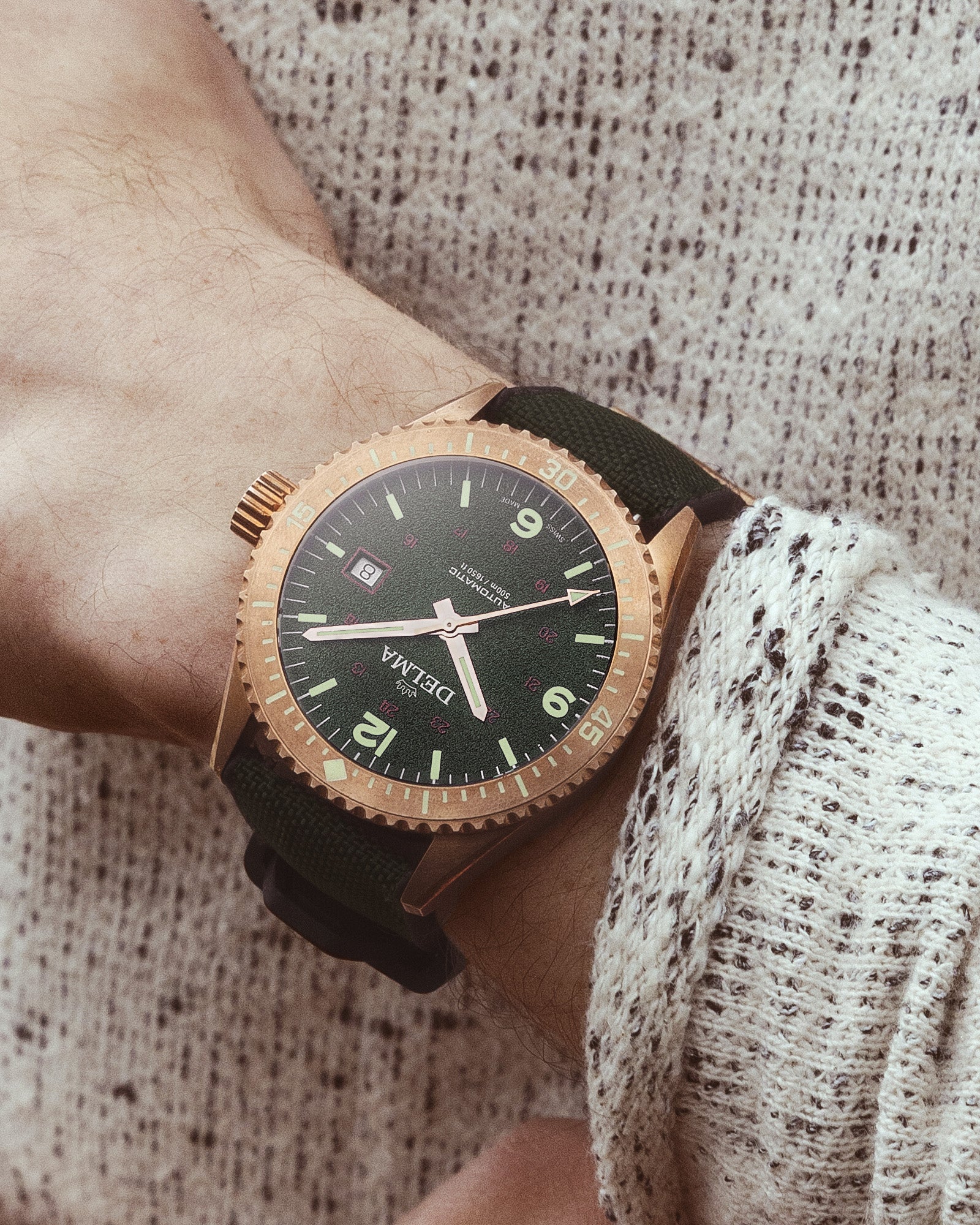 DELMA Cayman Bronze watch with green dial and green Cordura strap on wrist