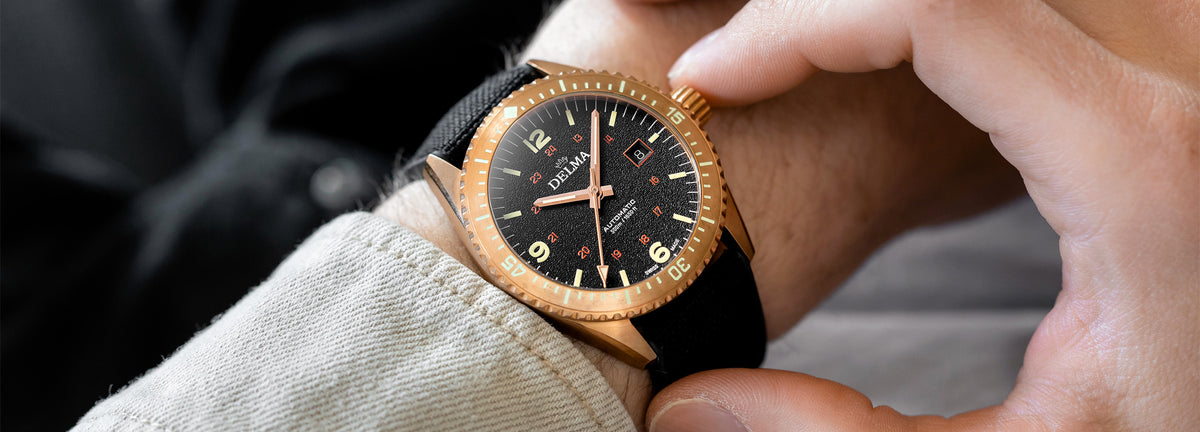 DELMA Cayman Bronze watch with black dial and black Cordura strap on wrist