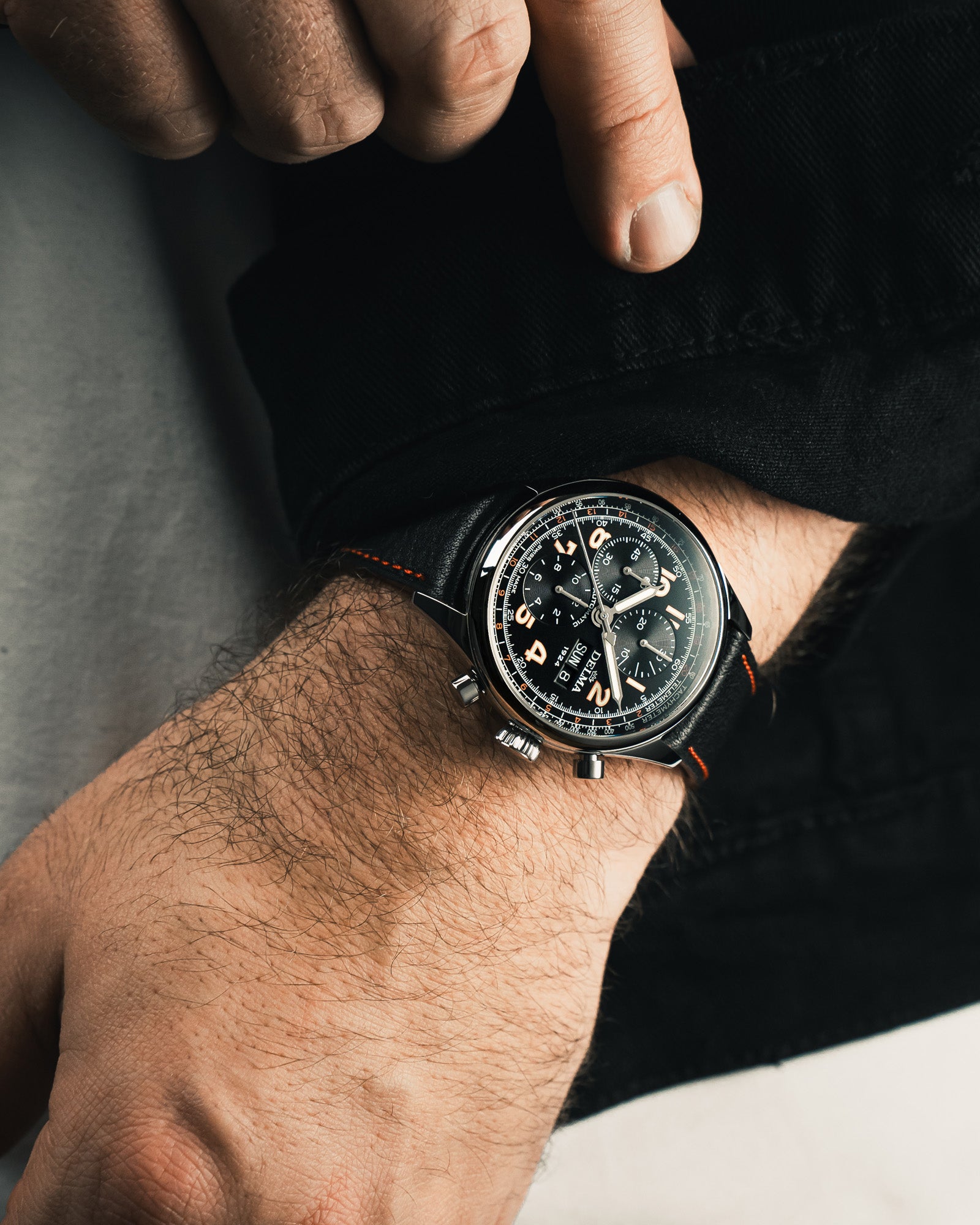 DELMA Heritage Chronograph 100 Years LE stainless steel watch with black dial and black leather strap on wrist