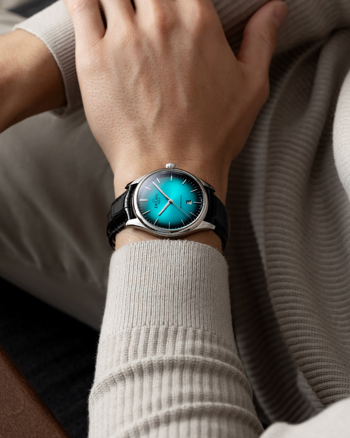 DELMA Heritage Automatic stainless steel watch with teal fumé dial and black leather strap on wrist