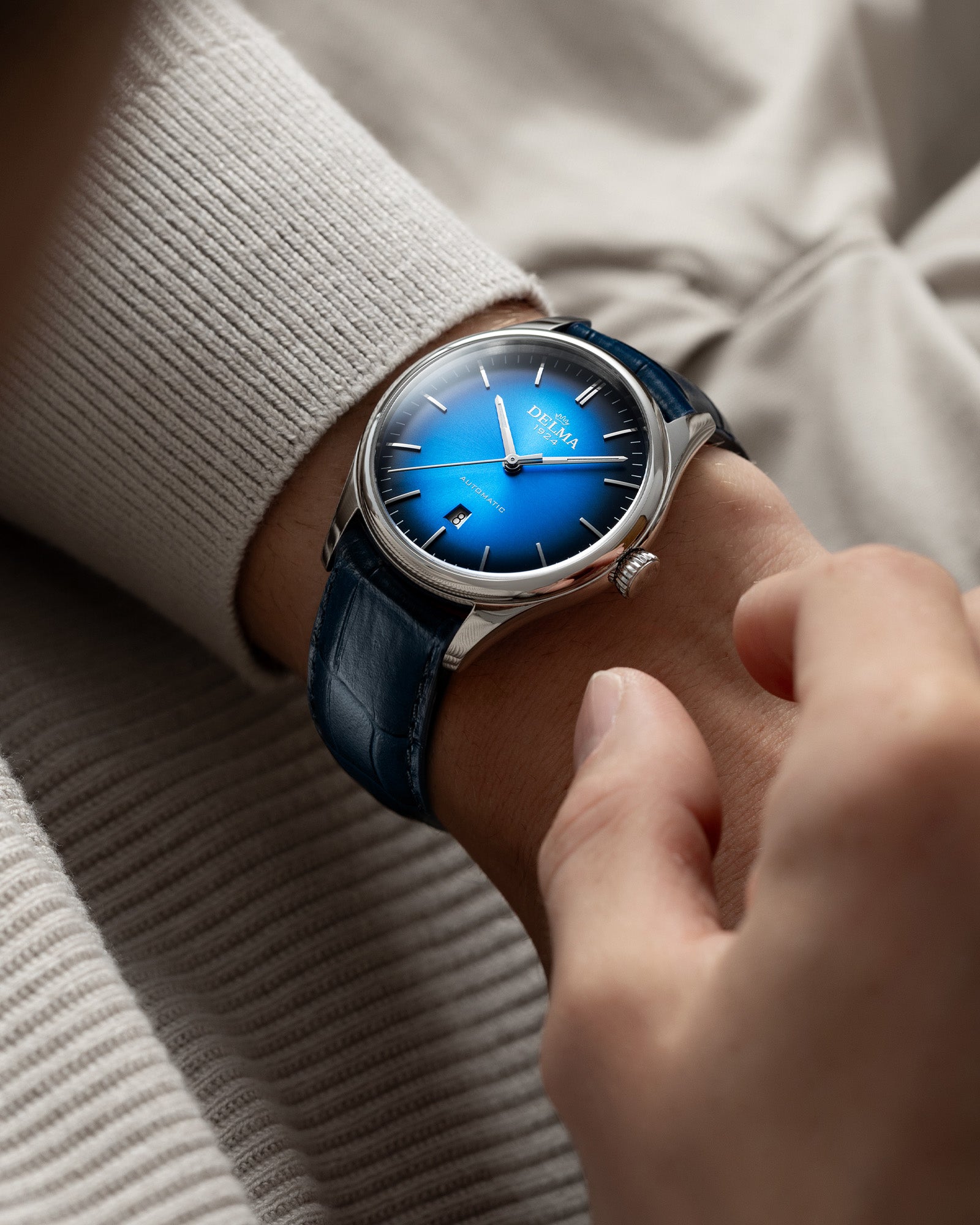 DELMA Heritage Automatic stainless steel watch with blue fumé dial and blue leather strap on wrist