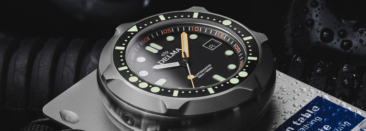 DELMA Quattro stainless steel watch with black dial and black bezel on decompression plate