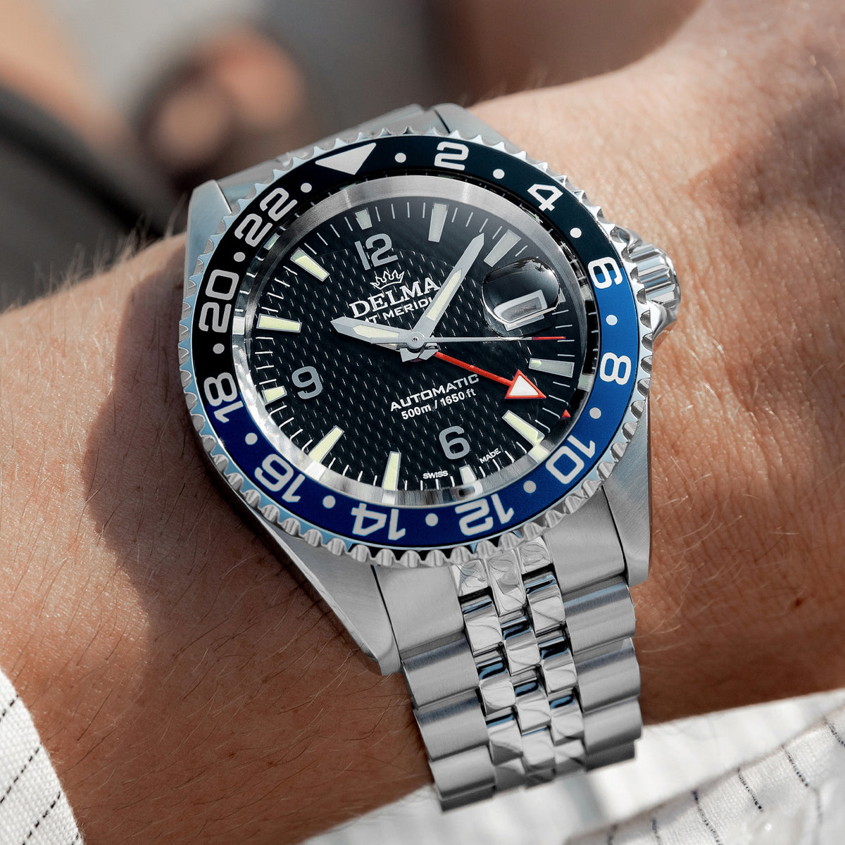 DELMA Santiago GMT Meridian Automatic stainless steel watch with black dial and black and blue bezel on wrist