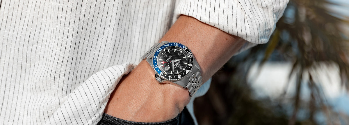 DELMA Santiago GMT Meridian Automatic stainless steel watch with black dial and black and blue bezel on wrist