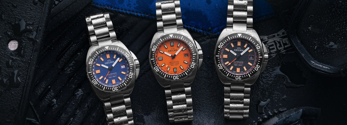 DELMA Shell Star Titanium watches in blue, orange and black dial with black bezel on dive gear